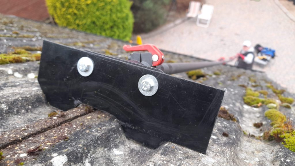 Tiled roof cleaning to remove the moss safely with a scraper attached to a long telescopic pole allowing the operator to stay on the ground