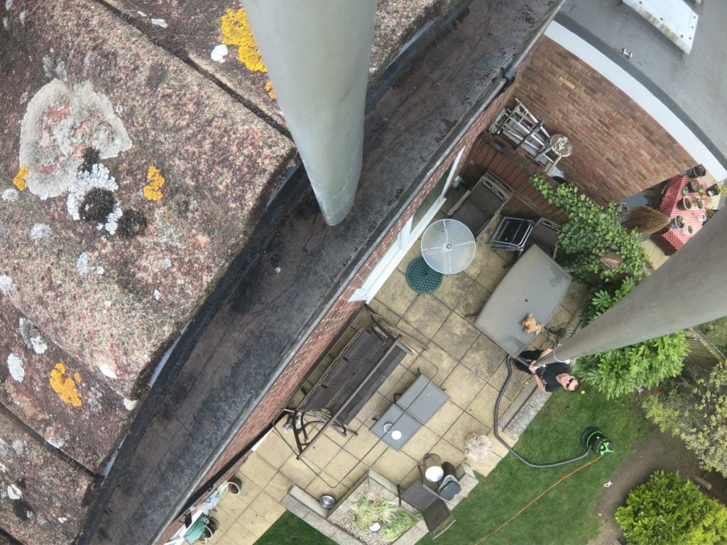 Cleaning gutters with a gutter vac. The nozzle is moving along the gutter sucking up the debris in the gutter while the operator is safely on the ground