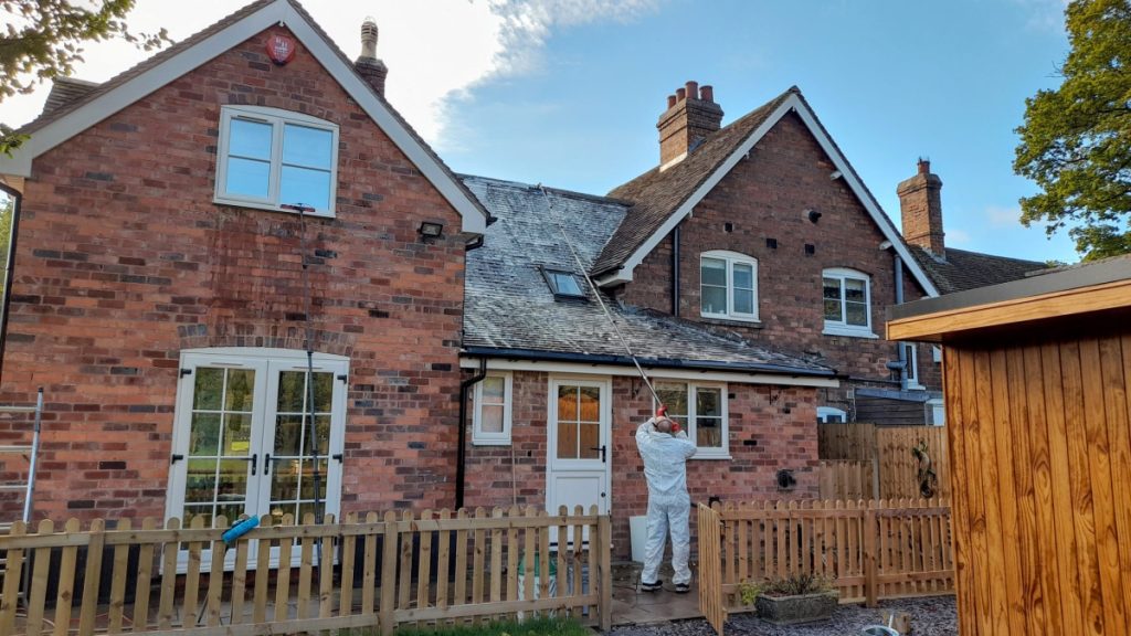 Applying biocide to a house roof to clean the tiles and remove moss and algae