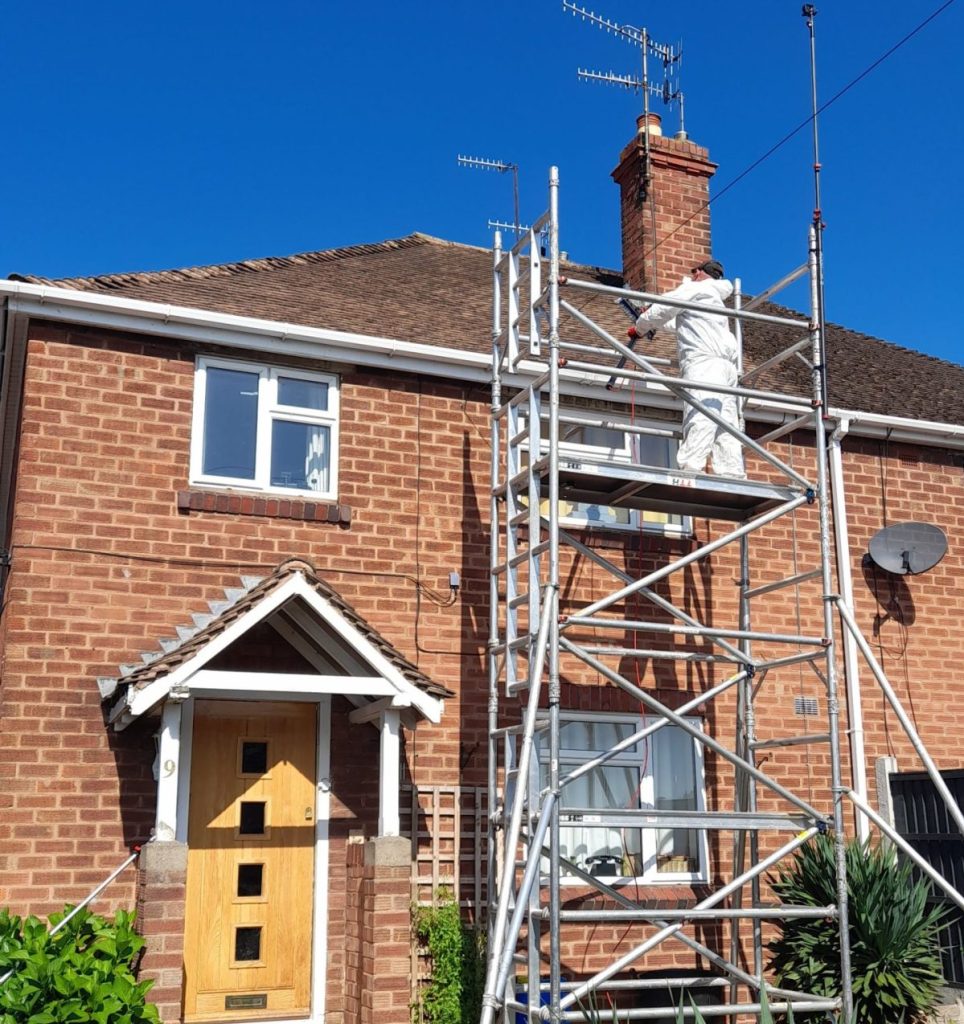 Roof cleaning a two storey house from a scaffold access tower to remove the moss