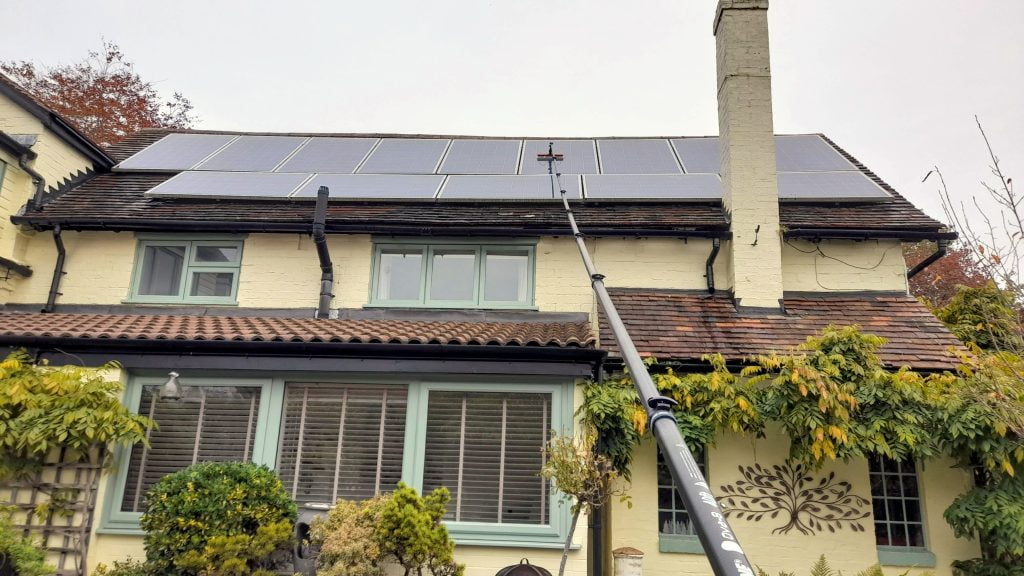 Cleaning a residential solar panel array from the ground. A long telescopic window cleaning pole is used along with pure water for the best results