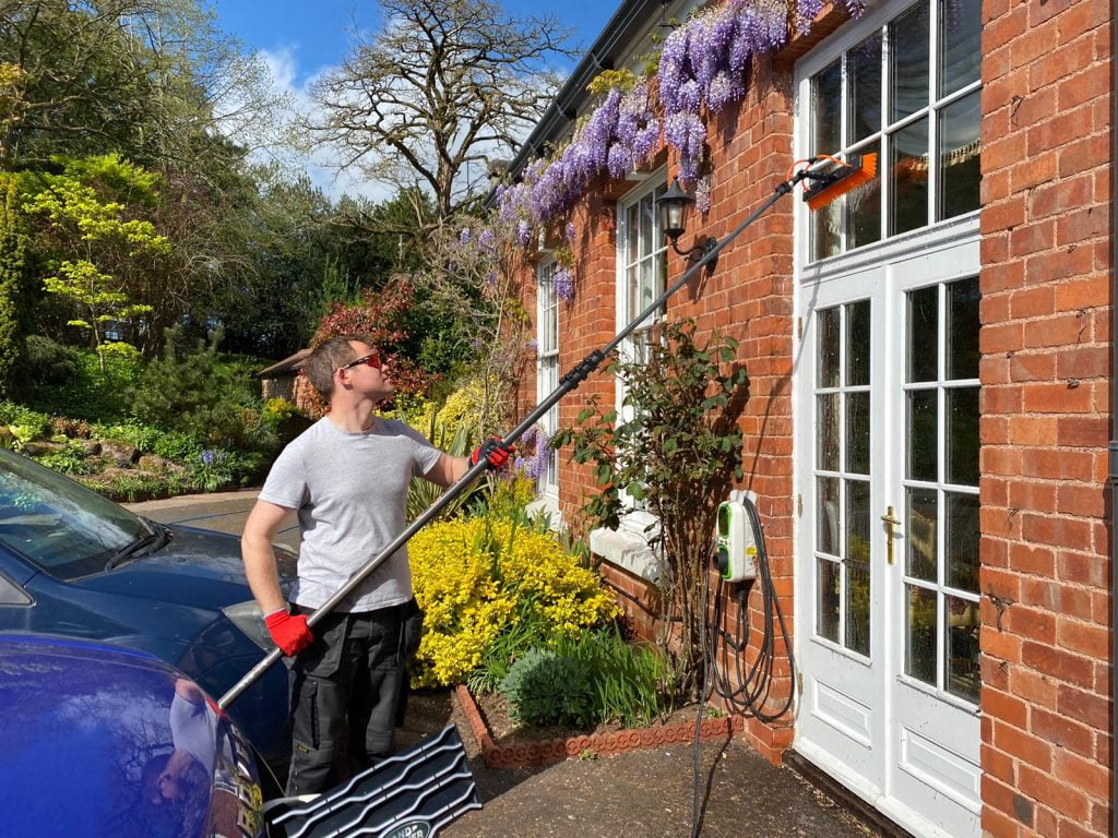 Cleaning the windows at a large country house with a water fed pole and pure water to leave the windows spotless and streak-free