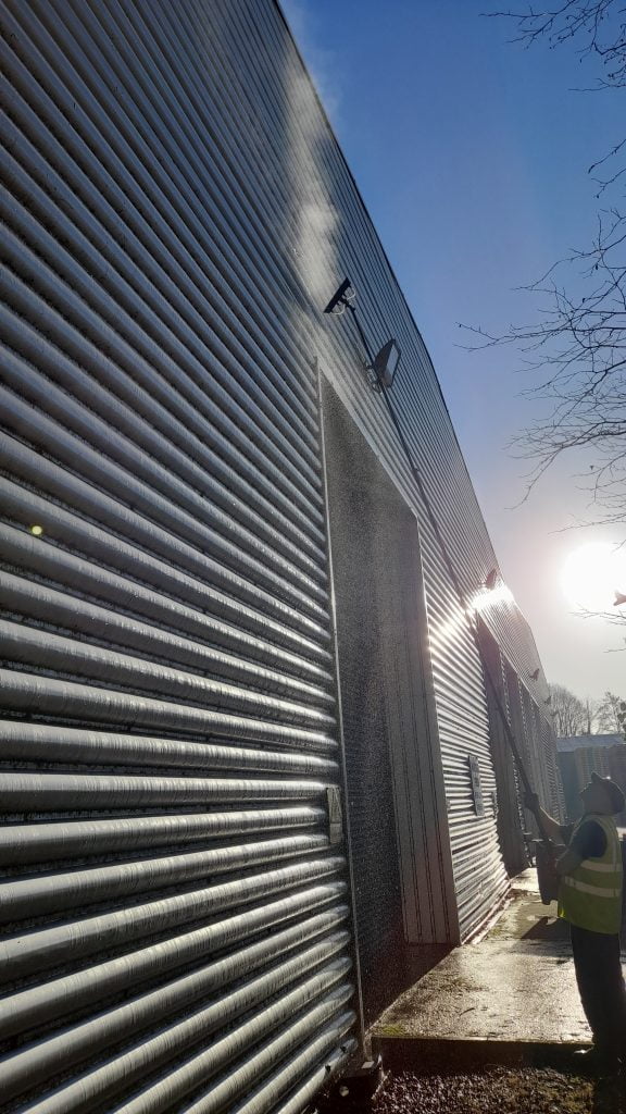 Cleaning a factory's metal cladding with hot water through a telescopic brush