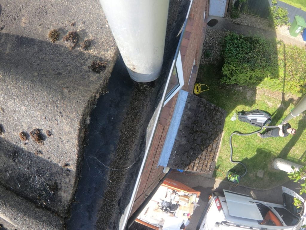 Cleaning gutters with a gutter vac. The nozzle is moving along the gutter sucking up the debris in the gutter while the operator is safely on the ground